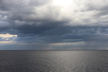 Fototapeta premium Dark storm clouds over calm water before rain