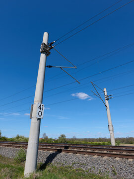Transportation / Railway: Two modern catenary posts with kilometer and hectometer markers at an electrified railroad track in Central Germany
