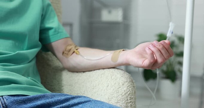 Man with IV drip in armchair at hospital, closeup