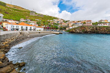 Fototapeta premium The small pebble beach, vineyards and fishing village at Camara de Lobos, Portugal, on the Atlantic Island of Madeira in the Atlantic Ocean.