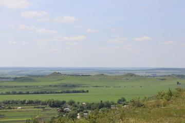 Obraz premium Rolling green hills and countryside panorama under blue summer sky