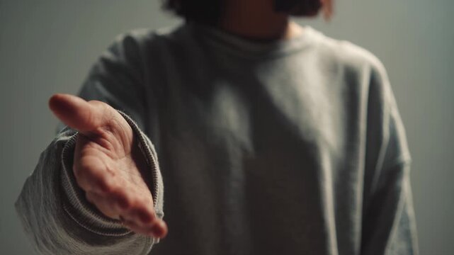 Person extending open hand toward camera offering help or handshake gesture