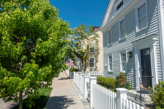 A row of houses on a tree-lined sidewalk on Main Street in the New England town of Essex, CT in spring