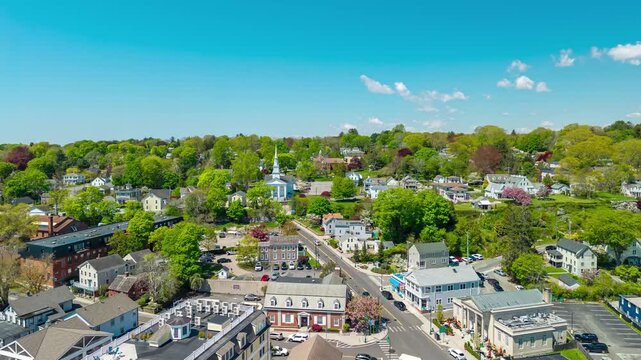 Mystic historic town center aerial hyperlapse, a bright drone push timelapse moving past downtown waterfront buildings toward the white steeple of the Congregational Church in Mystic, Connecticut.
