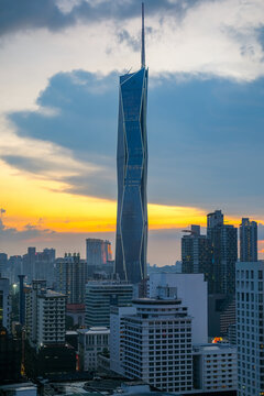 Dramatic skyline of Bukit Bintang in Kuala Lumpur featuring a towering skyscraper rising above surrounding city buildings during sunset, showcasing modern urban architecture and vibrant metropolitan