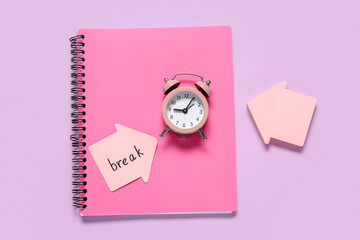 Fototapeta premium Alarm clock with notebook and word BREAK on sticky note against lilac background. Time management concept