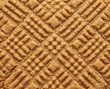 Textured surface background of a traditional peanut butter cookie with geometric cross hatch fork pattern