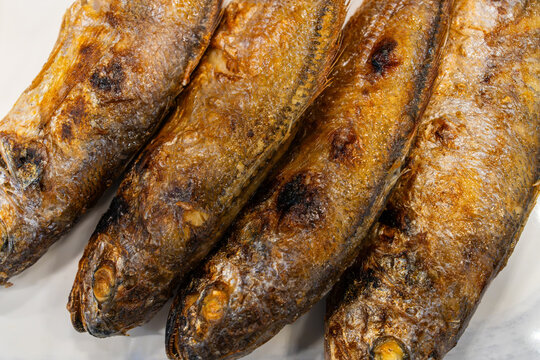 Extreme close-up of golden-brown grilled whole dried yellow croaker fish