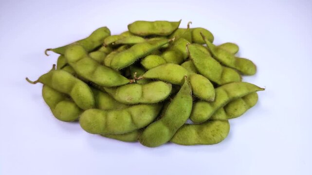 白背景で回転する生のだだちゃ豆（枝豆）のクローズアップ
