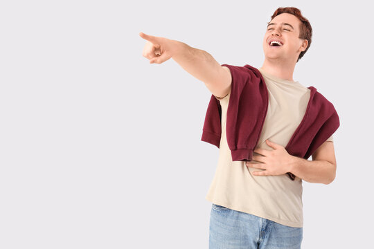 Young man laughing at something on white background. Accusation concept