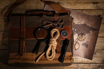 Bag with travel equipment, world map and keys on brown wooden background © Pixel-Shot