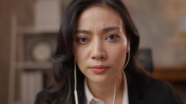 Portrait woman office business serious thoughtful adult asian closeup indoors, closeup portrait of worried young woman wearing earphone indoors looking camera with serious expression, close up