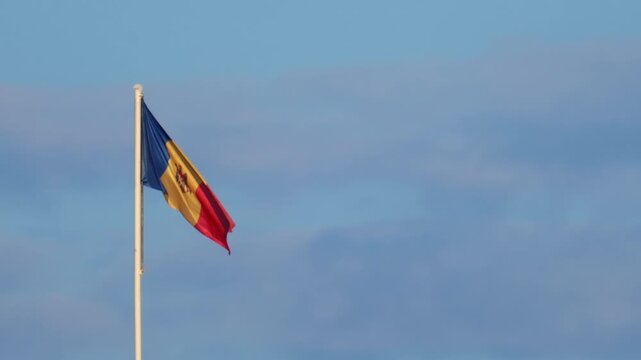 Moldovan national flag waving on a tall flagpole against a clear blue sky