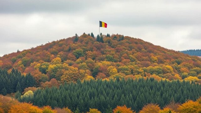 Autumn forest landscape with colorful fall foliage on a hill and a national flag flying at the summit