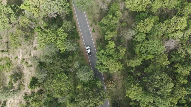 Aerial drone footage of a pickup truck driving on a rural road through countryside landscape. Scenic view of travel, transportation, and freedom in nature