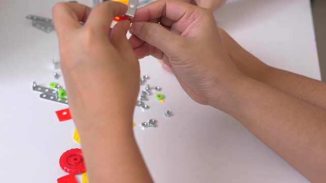 Close up of child hands assembling 3D printed robot model on table. Concept of STEM education, robotics learning, creativity, and technology development