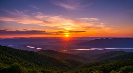 Obraz premium Vibrant sunset over rolling hills landscape with colorful sky and sun