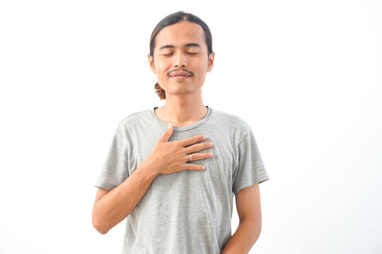 Young handsome Indonesian, Asian man in gery shirt positive expression, joyful and exciting isolated on white background. Happy adorable glad man rejoices success
