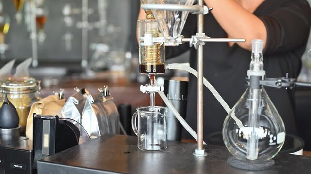 Specialty Coffee Extraction with Laboratory Glass Spiral Coil Brewing System, Barista Using Scientific Glassware Apparatus in Modern Cafe