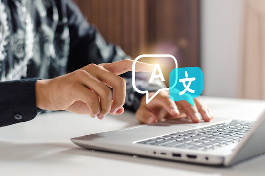 Businessman touching digital language translation icon on laptop keyboard at desk. Translation icon, symbolizing international trade, linguistic inclusivity, advanced machine learning