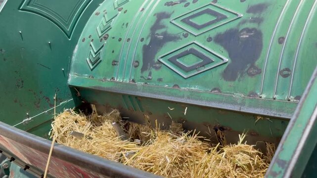 Mechanized thresher separates bajara grains from pearl millet straws, modern haymaking in traditional fields.