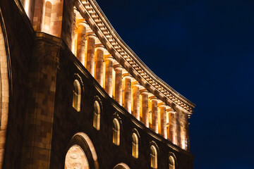 Fototapeta premium Illuminated the Government of Armenia building at night, Yerevan. Dramatic night view of a classical stone building facade