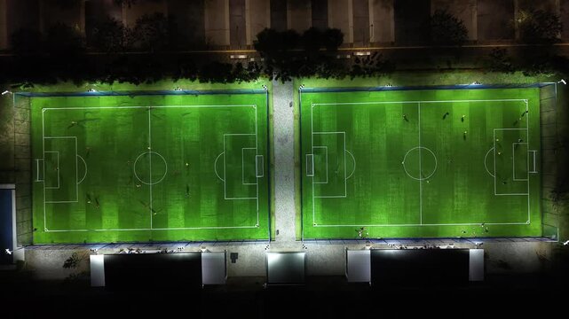 Aerial Drone View of Night Football Field with Players Training on Illuminated Artificial Turf