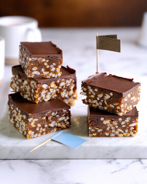 Chocolate puffed rice bars with peanuts and dark chocolate glaze on marble background