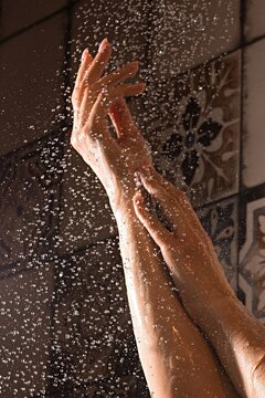 Woman's hands under shower water in bathroom at daytime