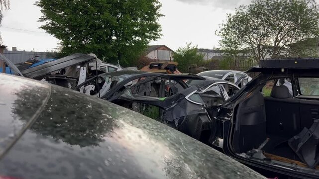 Electric car junkyard. Car beyond repair after accident. Car rusting in junkyard. Scrap metal being recycled. Dismantling of spare parts, scrap metal recycling.