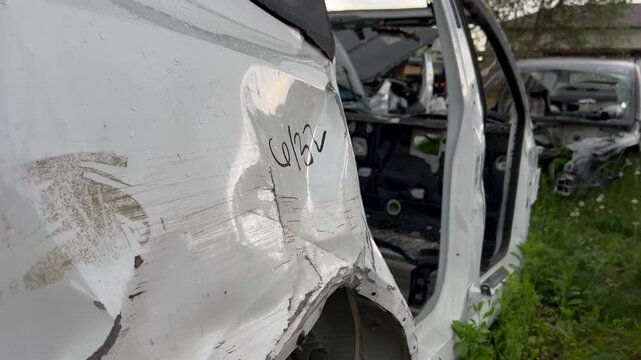 Electric car junkyard. Car beyond repair after accident. Car rusting in junkyard. Scrap metal being recycled. Dismantling of spare parts, scrap metal recycling.
