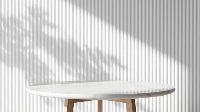 A round white marble tabletop with light-colored wooden legs positioned against a white corrugated vertical slat wall featuring natural tree leaf shadows and soft daylight.