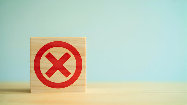 Symbolic red X mark on a natural wooden block, representing wrong, error, denial, or cancellation, set against a clean, minimalist blue background, conveying themes of correction and choice