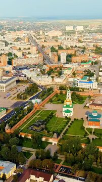 Vertical video. Tula, Russia. Tula Kremlin, red-brick fortress walls and nine towers rising above the Upa River, sweeping aerial panorama over the historic city center under a bright summer sky. Dron