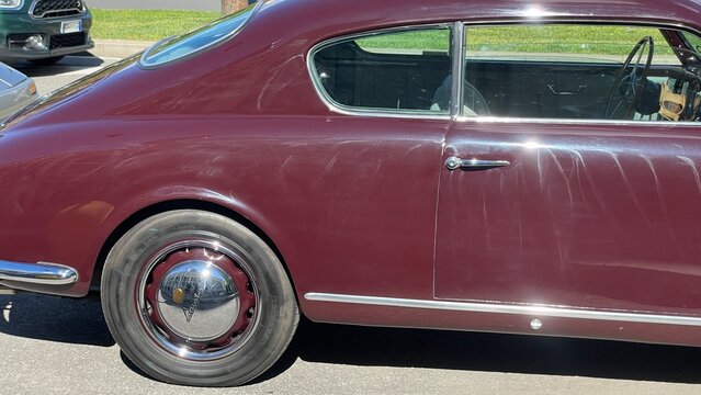 Classic Burgundy Coupe: A detailed shot of a vintage burgundy coupe, highlighting its elegant lines, chrome details, and classic wheel. A timeless automotive design captured from the side.