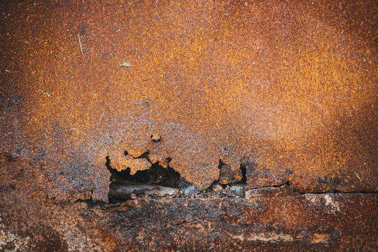Rusty metal sheet with cracked edge and exposed fastener