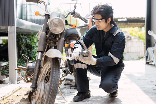 Garage mechanic male worker checkup, fix, replace, service old motorcycle motor bike in workshop.