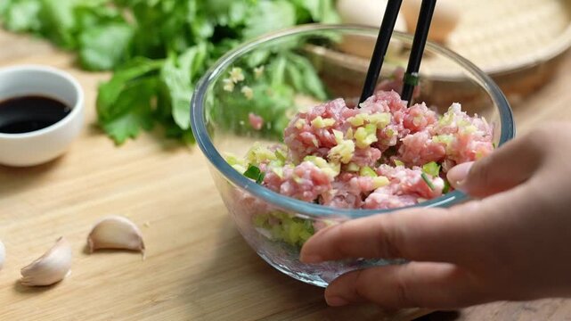Mixing Ground Meat with Chopped Vegetables in Glass Bowl