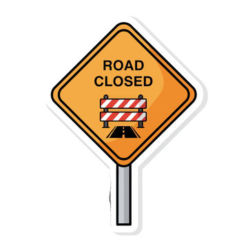 A road closed sign with a barrier warns of a blocked path ahead for vehicles and drivers