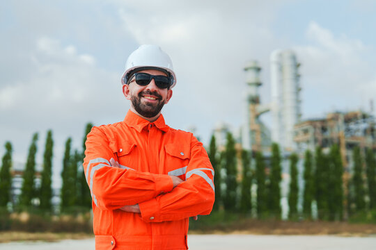 Oil and gas refinery in petroleum industry, industrial worker safety helmet sunglasses orange uniform confident smiling refinery plant engineer