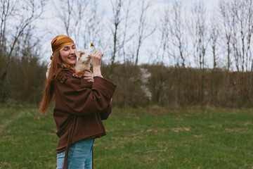 Fototapeta premium Lifestyle woman outdoors with a goat kid in a field, sharing a playful moment, showing affection and joy against a rustic countryside backdrop.