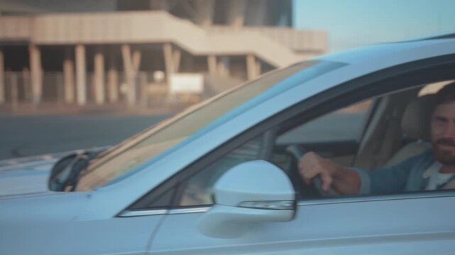 Smiling white man in silver car during test drive, Relaxed driver in denim enjoying peaceful morning test drive scene