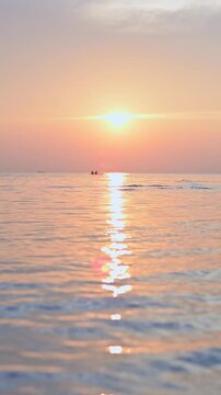Vertical shot romantic scenery of the sea with unrecognizable couples on kayak during sunset at koh samui. Thailand. Far focal length.