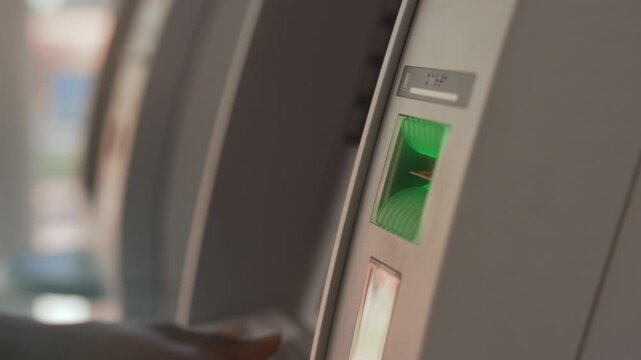 Person uses ATM machine securely, Closeup of person making secure transaction at ATM terminal during daytime