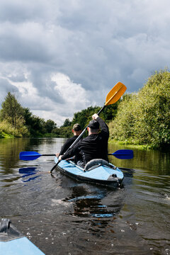 Two Men Paddling Blue Kayak On River