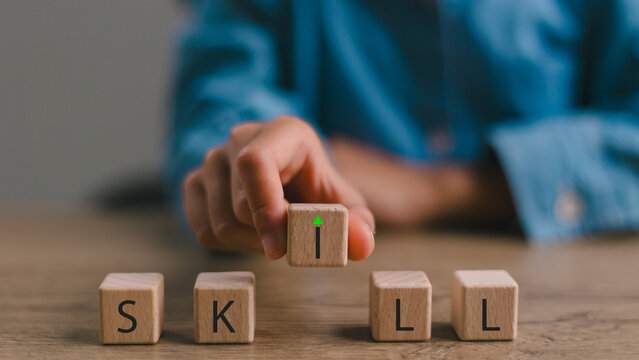 Upskilling and Skill Enhancement Concept. A hand lifts the &ldquo;I&rdquo; block in SKILL, forming a gap with an upward arrow, symbolizing upskilling, progress and continuous improvement in workforce capability