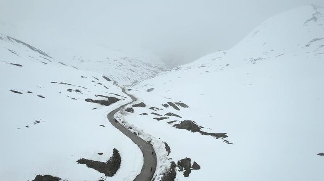Aerial drone side move shot showing the Shingo La Pass road amid snow covered Himalaya mountains during snow fall showing the cold and beautiful environments of Ladakh, Leh, Sissu and Himachal Pradesh