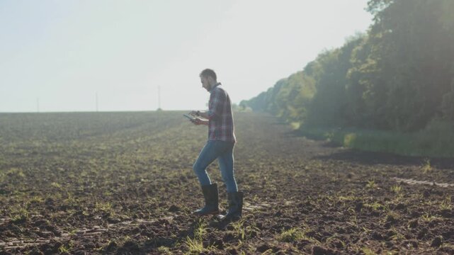 Individual dressed in boots and plaid shirt carefully collects soil samples during morning inspection
