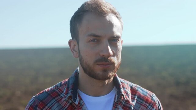 Rugged farmer stands in wide open field under quiet sunlight demonstrating reflective mood and natural environment