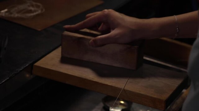 Hand opening wooden drawer in dim workspace